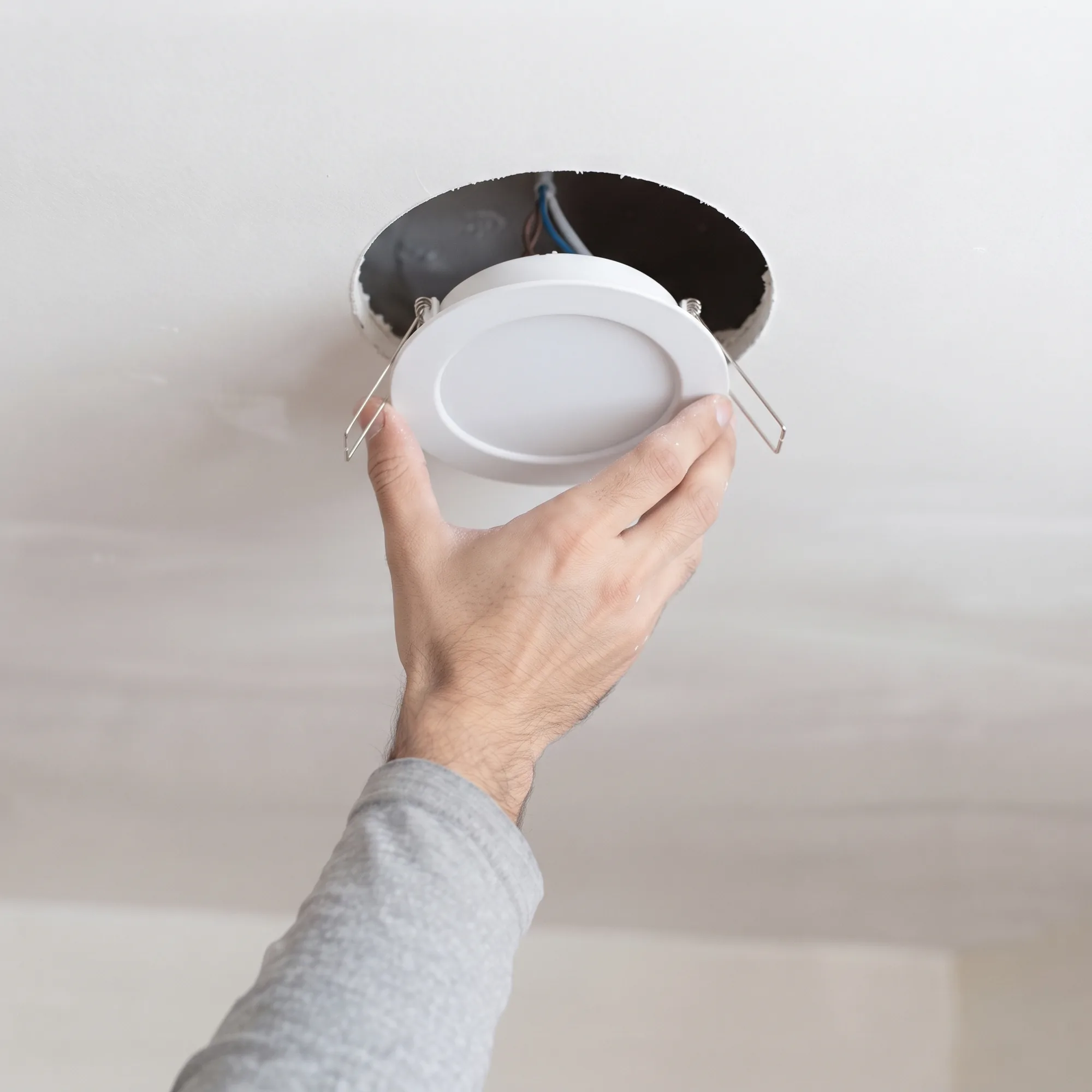 Cómo instalar un downlight, paso 4: meter el aro en el hueco del techo con los muelles