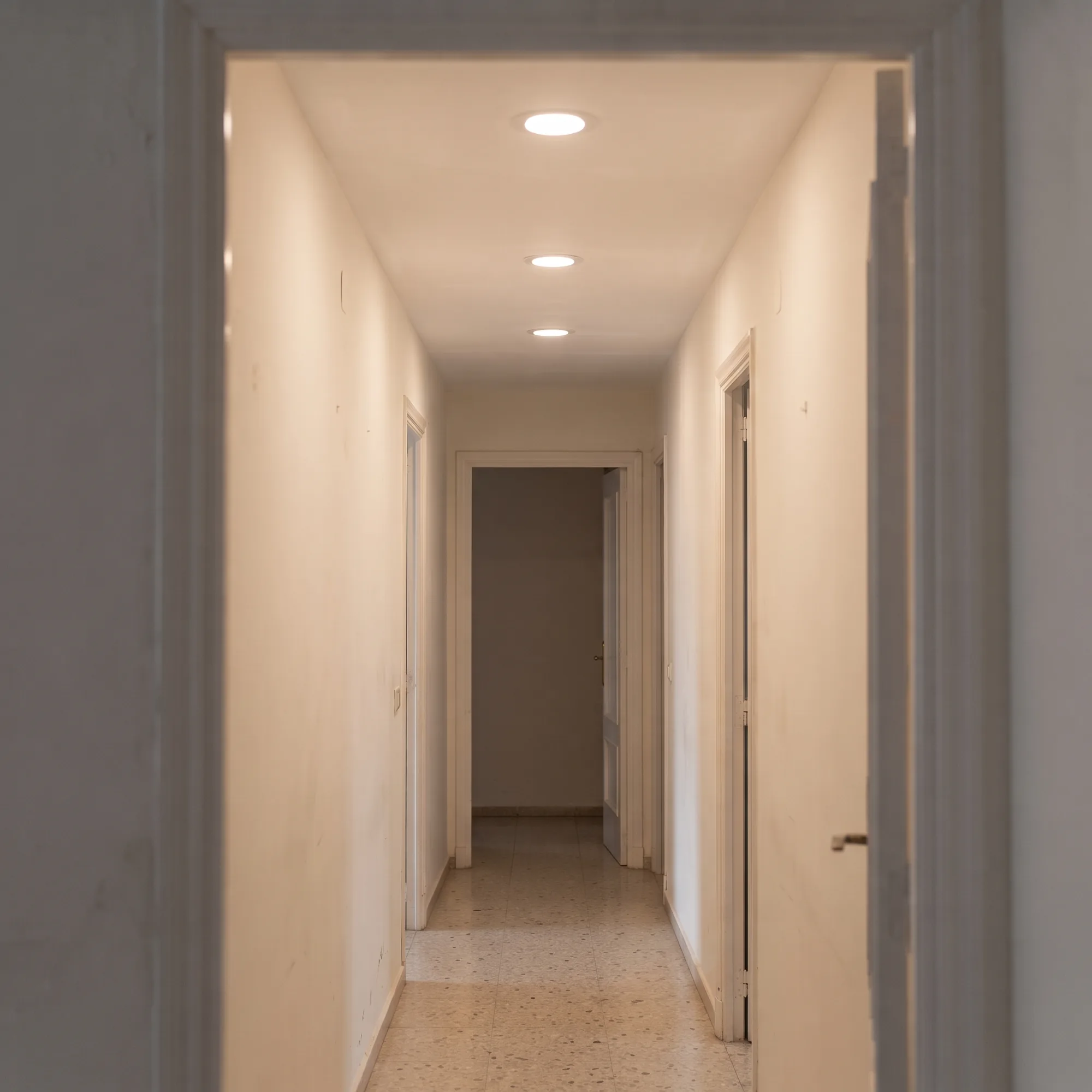 Cómo instalar un downlight, paso 5: tres downlights LED encendidos y alineados en el pasillo